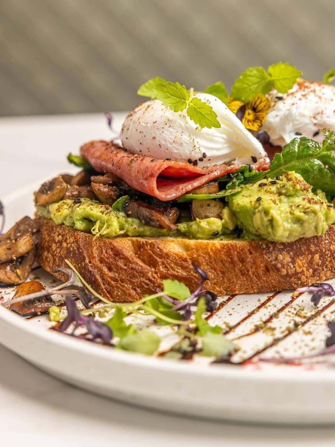 Sourdough avocado toast topped with poached eggs, crispy prosciutto, and micro greens — Zen's signature brunch plate.